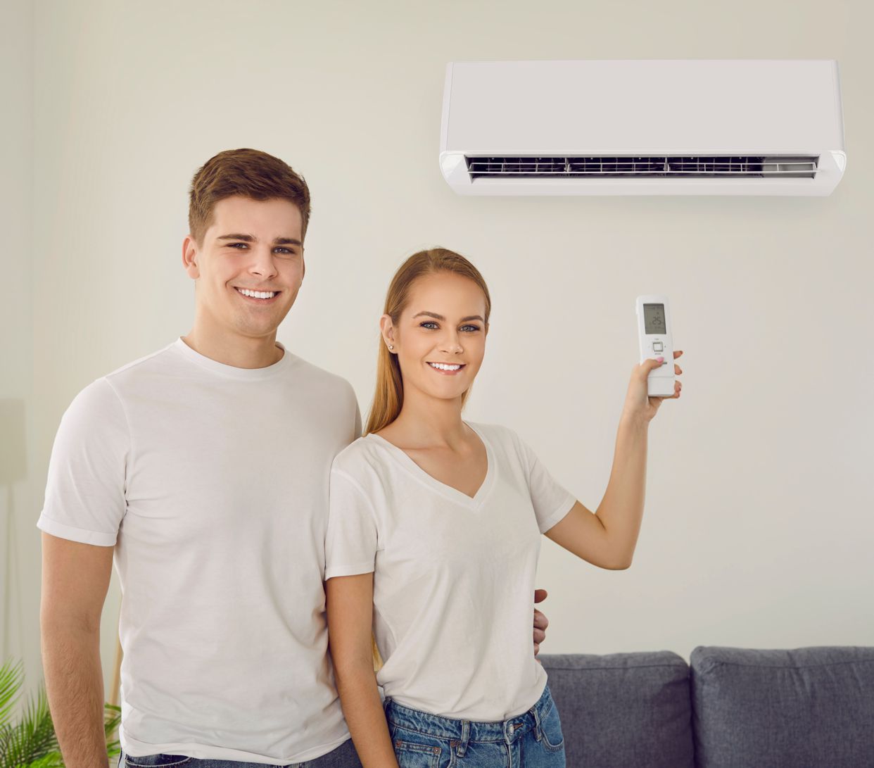 Par podešava klima uređaj u dnevnom boravku Sretni bračni par koristi moderni klima uređaj kod kuće, podešavajući temperaturu pomoću daljinskog upravljača.